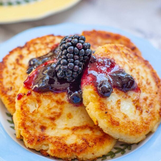 a close up of cheese pancakes on a plate topped with berries