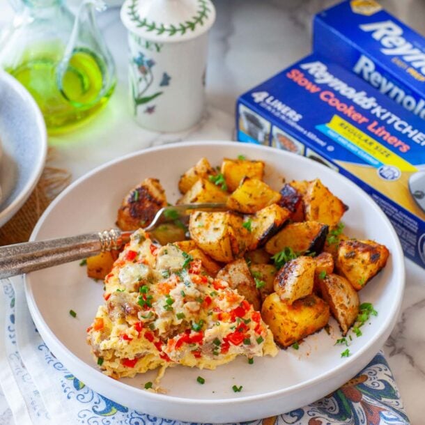 A closeup image of egg casserole and baked potatoes on a plate, on a table.