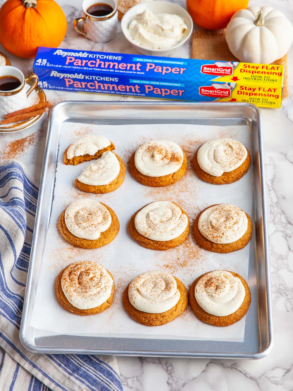 Frosted cookies on a baking sheet, on a table with pumpkins and a box.