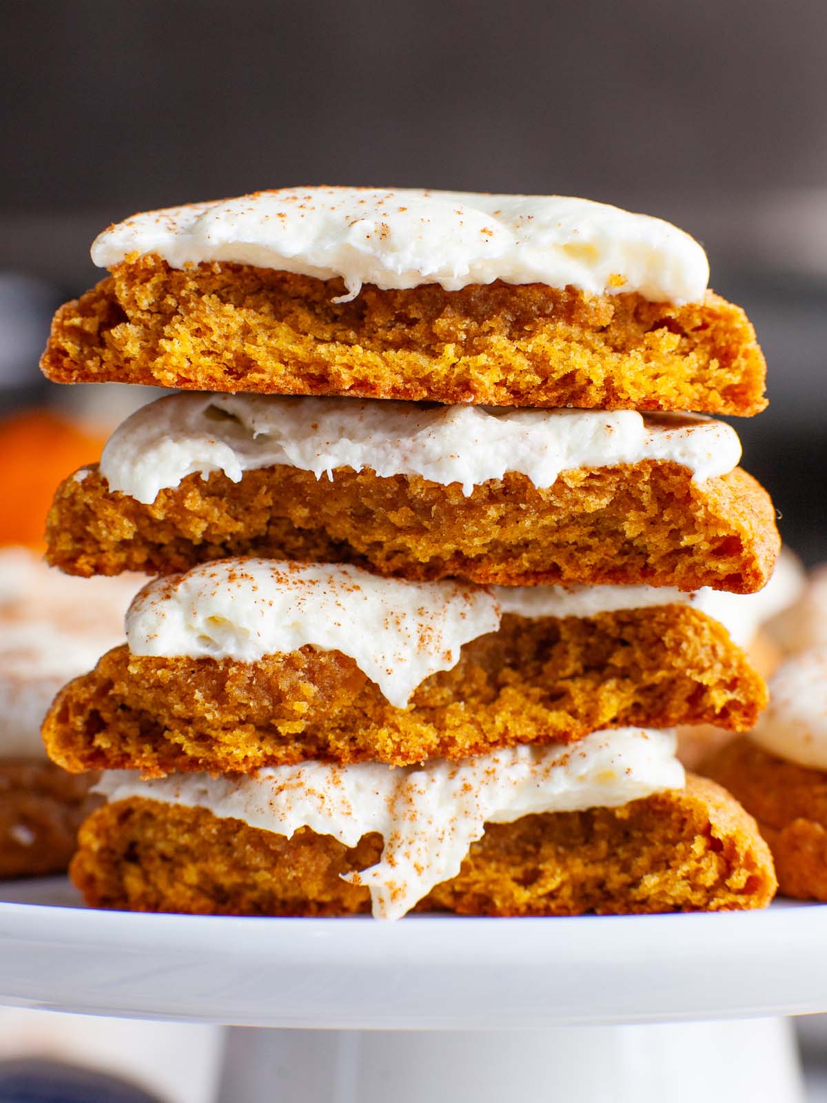 A closeup image of frosted pumpkin cookies cut open and stacked.