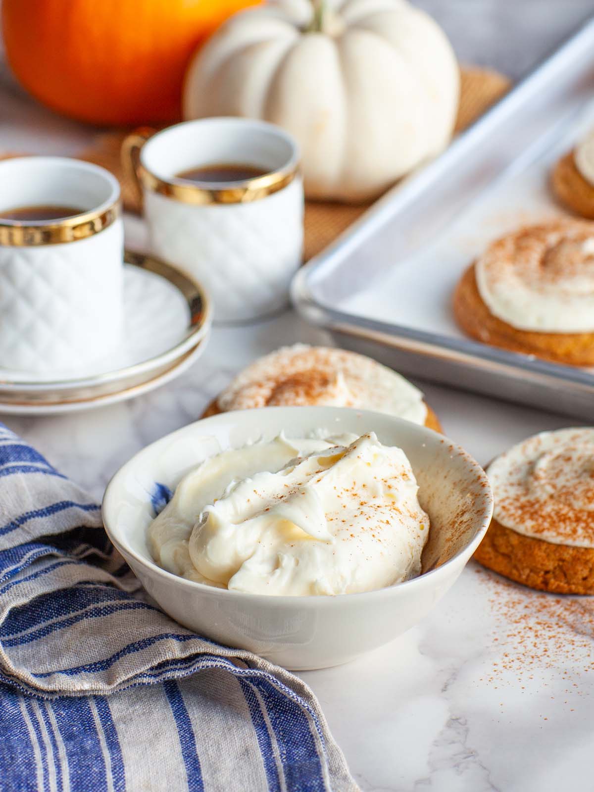 A closeup image of frosting in a bowl, on a kitchen table.