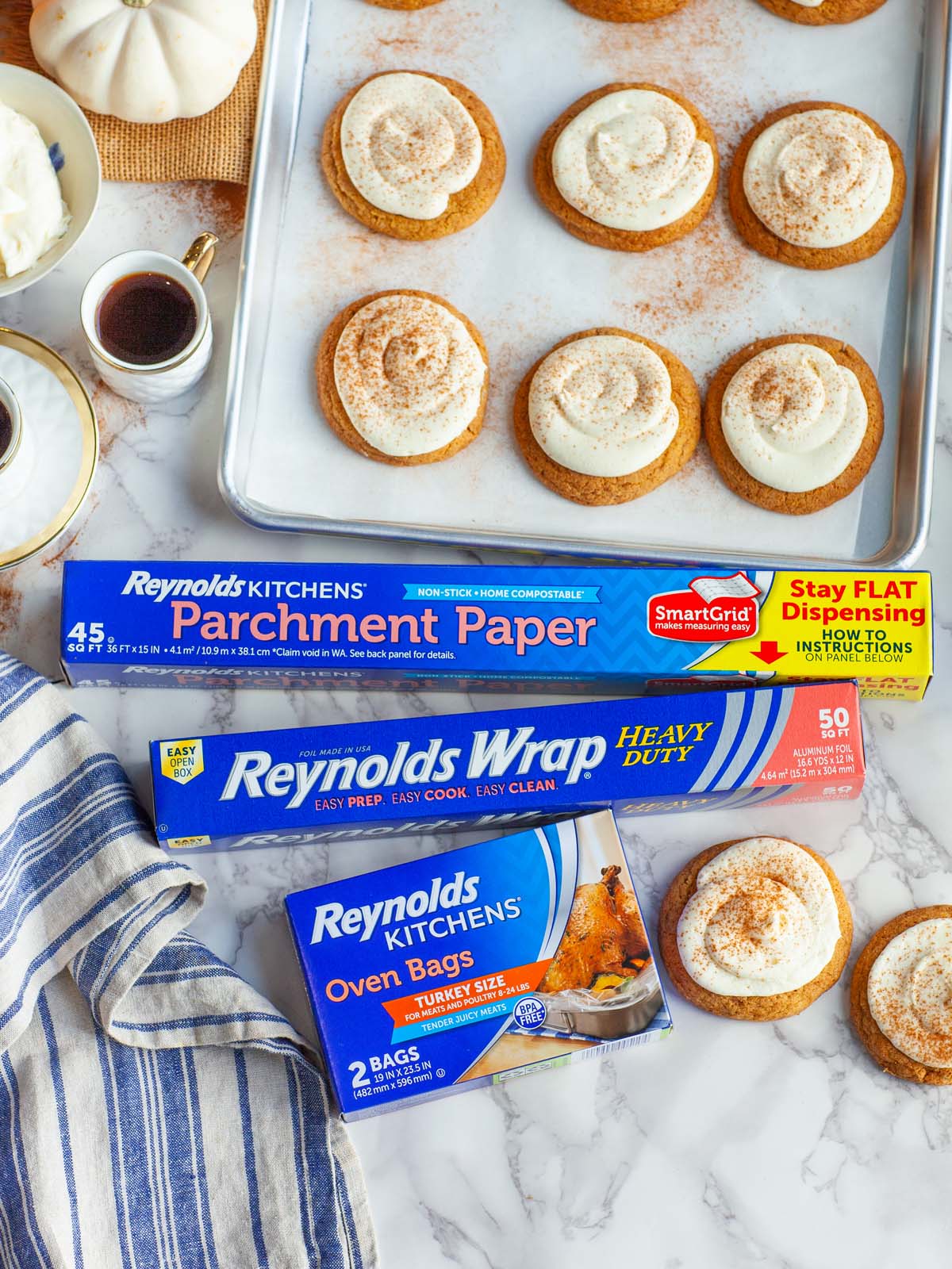 Several boxes of kitchen products on a table with a baking sheet filled with cookies.