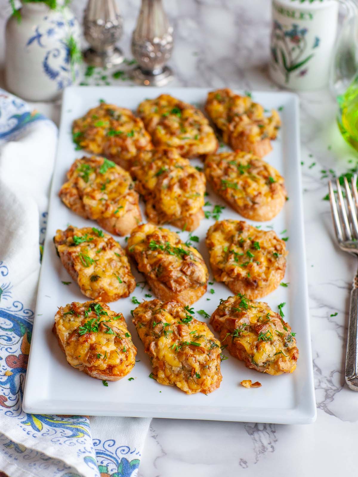 A serving tray on a kitchen table, filled with cheese crostini appetizers.