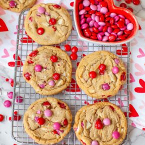 Brown butter cookies with pink and red M&Ms on a wire cooling rack, on a table with more candy.