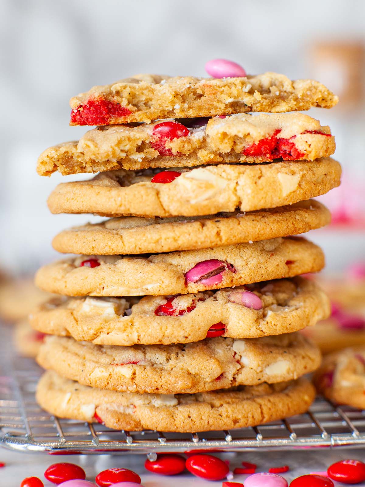 A closeup image of a cookie stack; cookies with pink and red M&Ms.
