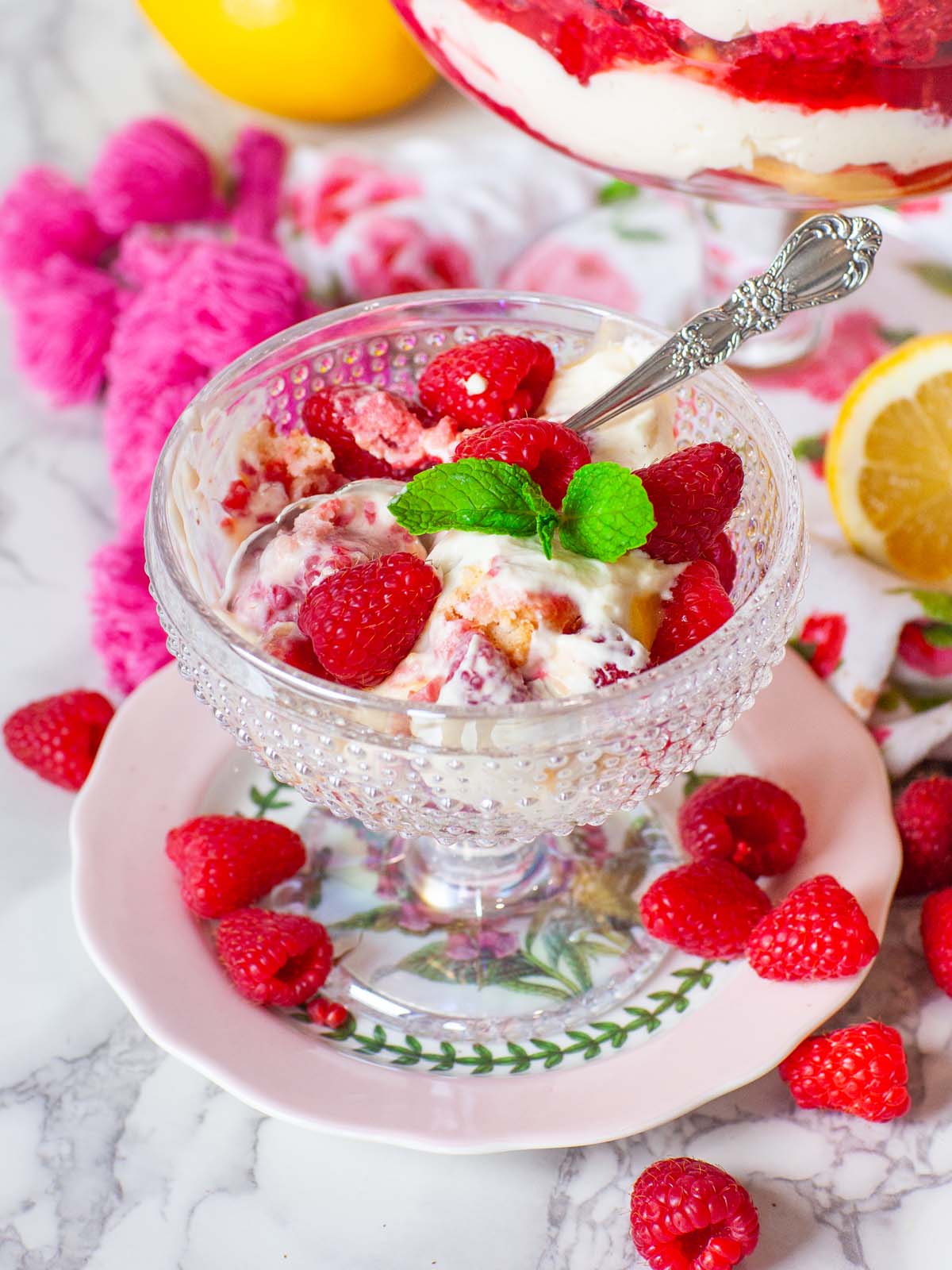 A closeup image of cream and raspberries in a small bowl on a table with raspberries.